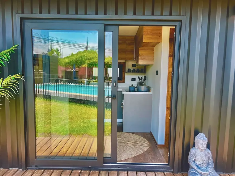 Puerta corredera de termopanel abierta hacia terraza con piscina