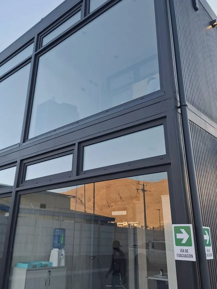 Fachada acristalada de dos niveles con perfilería grafito en edificio comercial
